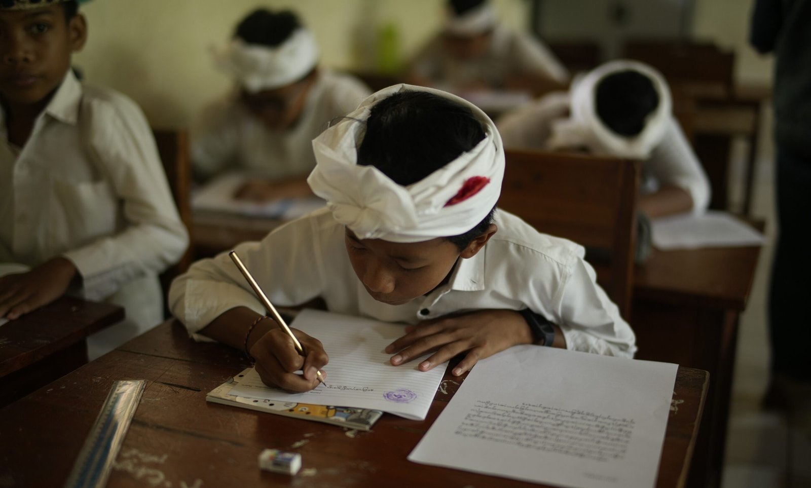 A young Balinese student reading a book, part of COCO Scholarship program